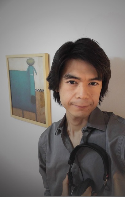 Takuto Fukuda hält seine Kopfhörer in der Hand und sieht in die Kamera.