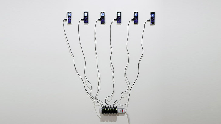 Installation on a wall out of six mobile devices connected to charger cables