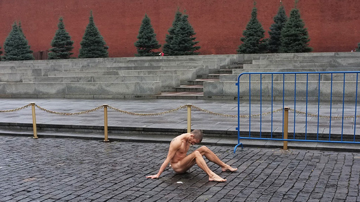 Ein nackter Mann sitzt auf der Straße