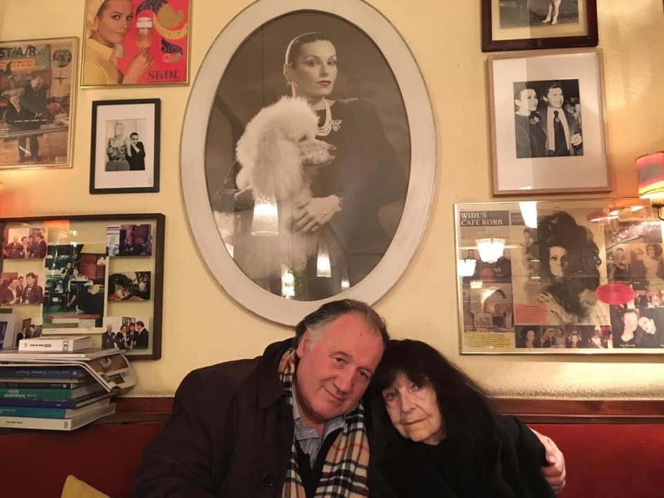 Peter Weibel mit Friederike Mayröcker vor einem Bildnis von Susanne Widl im Café Korb, Wien 2018.