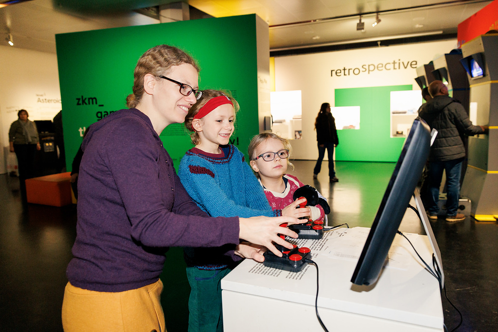Eine Frau und zwei Kinder an der Spielkonsole in »zkm_gameplay. the next level«
