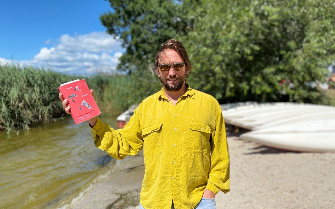 Mann in gelbem Hemd, der ein rotes Buch hält