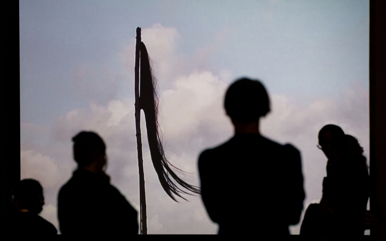 Zu sehen sind Schatten von Personen vor Edith Dekyndt Installation »Ombre indigène (Part 2, Martinique)«.