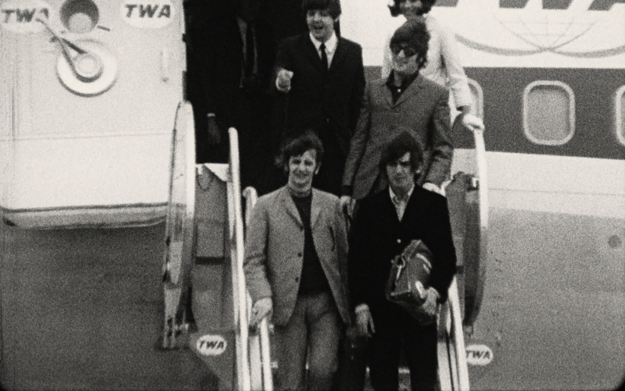 The picture shows a black and white photo of the Beatles.