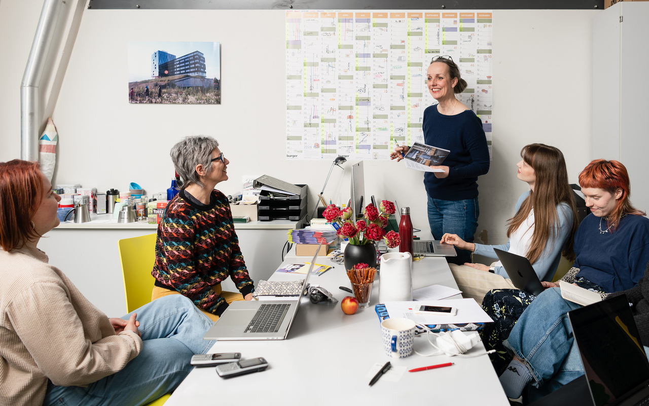 Five people with laptops in a meeting room.