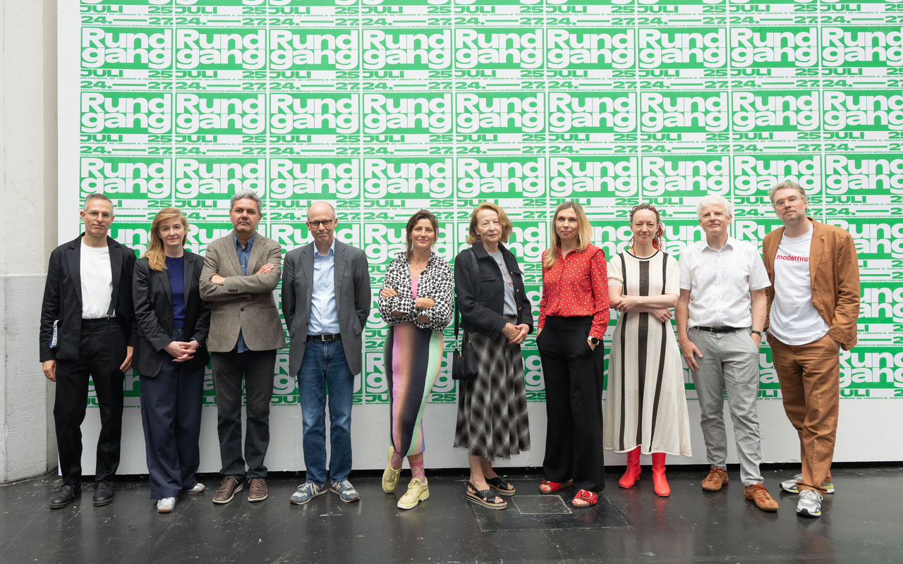Ten people can be seen in front of a large poster wall.