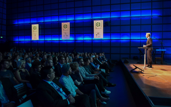 The audience of the AppArtAward award ceremony 2016 is sitting in the ZKM_Media Theater which is illuminated in blue light.