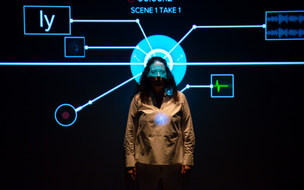 Noa Frenkel is standing in front of a projection. Her head is exactly in front of a circle and from this circle a mapping flows out in all directions.