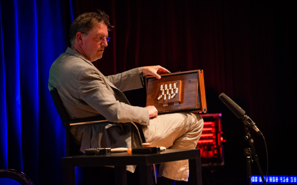 Manos Tsangaris creates sounds on a curious wooden instrument that resembles a combination of box and accordion.