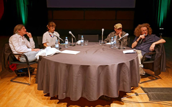 Vier Personen an einem Tisch mit Mikrophonen