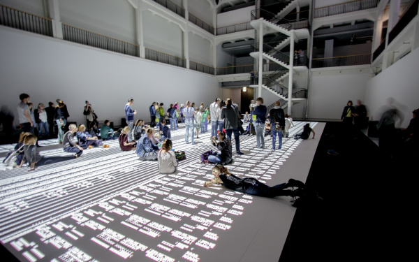 People sitting, lying and standing on a huge projection