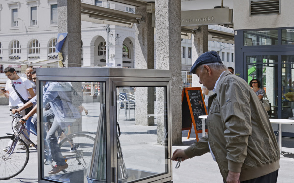 A man takes a silver megaphone from a glass cabinet