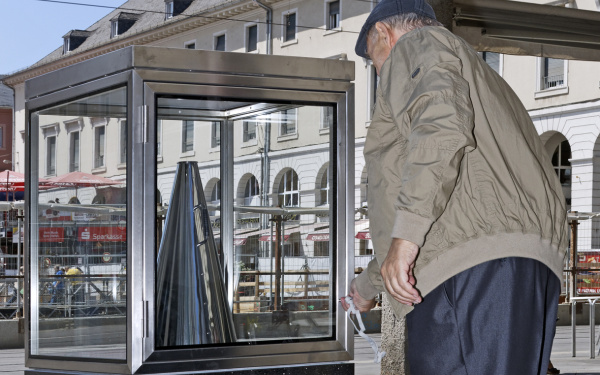 A man puts back a silver megaphone into a glass cabinet