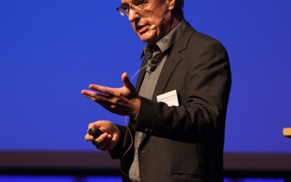  A man in a suit, standing on a stage.