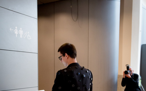 A person on whose jacket many cameras are in front of a terminal