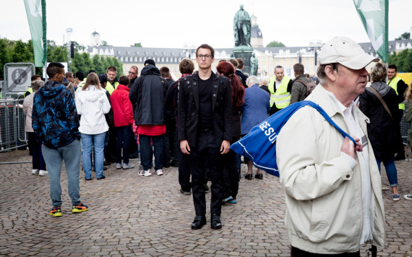 A person on whose jacket a many cameras are is standing in a crowd