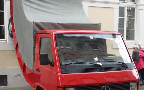 A red truck whose rear wheels stand at the wall