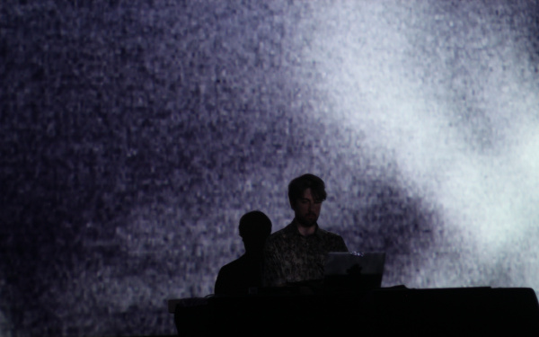 Man on stage in front of a laptop. Background dipped in white light