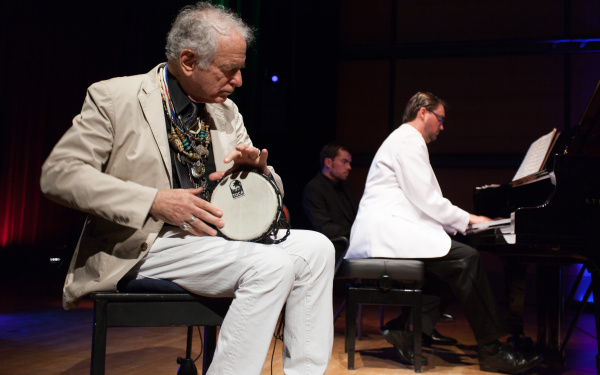 Ein Mann spielt eine kleine Trommel, ein anderer Klavier