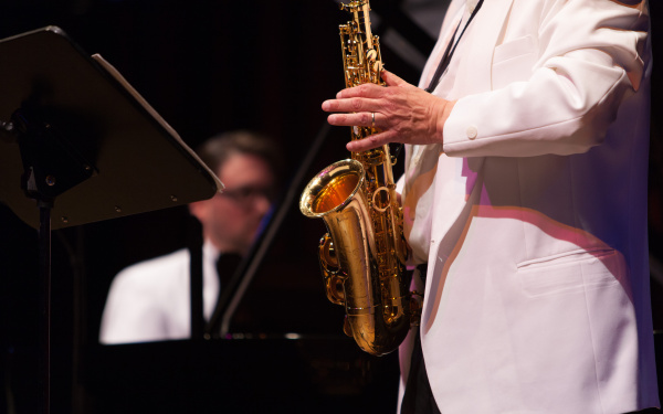 A man at the piano, in the foreground a saxophone