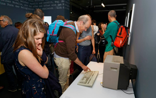 People standing in front of an old computer
