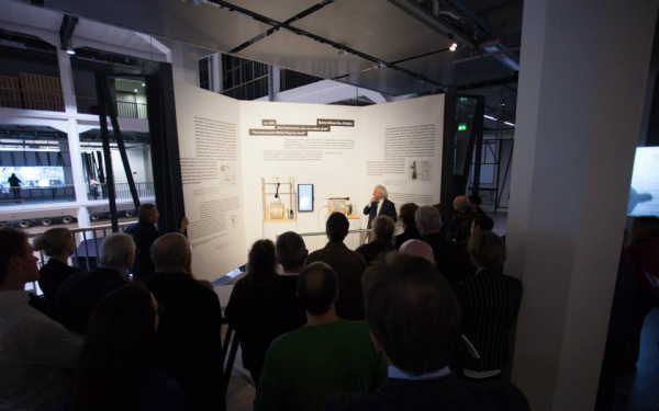 A man standing in front of a huge cardboard and talking to the public