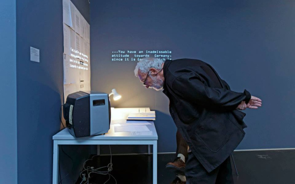 A man reading in front of a small screen the description