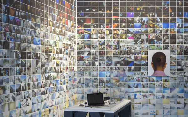 A rear wall with many small photos. In the foreground: A laptop on a table