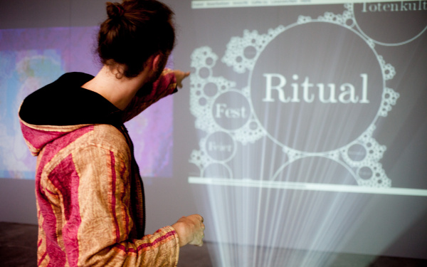 A person in front of a projection on which "Ritual" stands