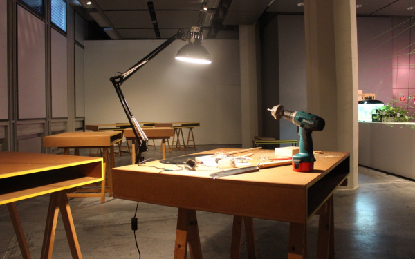 Ein Holztisch auf dem eine Lampe und eine Bohrmaschine steht