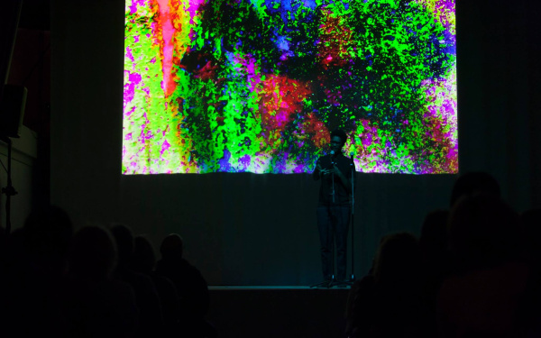 A man stands in front of a colorful screen