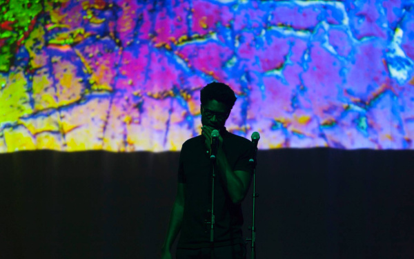 A man stands in front of a colorful screen