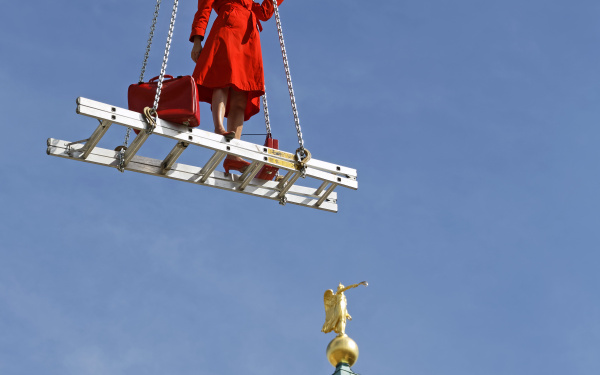 A blonde woman in a red dress on a floating ladder