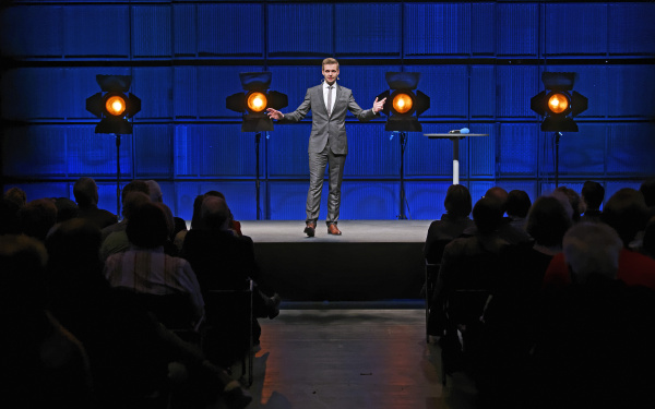 Ein Mann im Anzug steht auf einer Bühne.