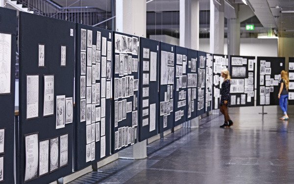 Two women are looking at the panels of Aby Warburg