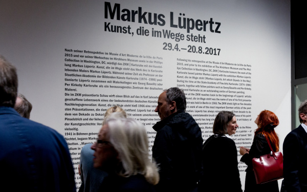 Das Bild zeigt Besucher vor einer Informationstafel zu Markus Lüpertz