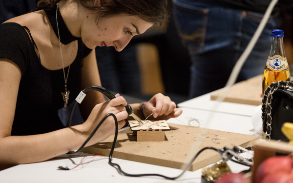 A woman is soldering a wire.