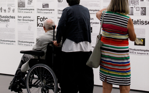 The picture shows three visitors in front of posters with typography 