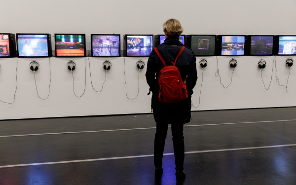 A woman is standing in front of a row of tube screens.