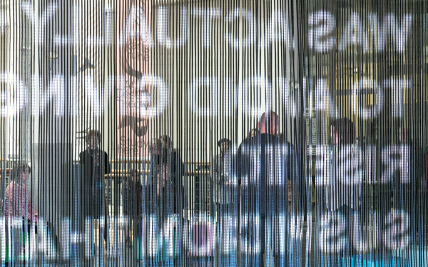 A curtain of glow sticks on which many bright colours and lettering are projected.