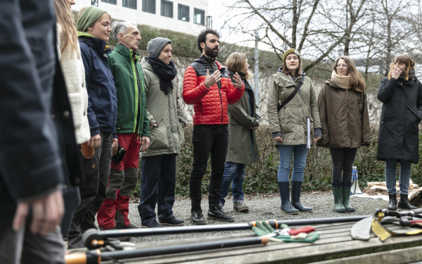 A group of people stand in front of garden tools as part of the tree-cutting course at the ZKM.
