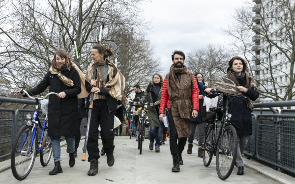 A group of people go in a procession with bicycles.