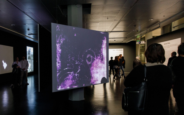 Foto von Menschen vor einer Leinwand mit einem abstrakten Video in Lila – Eine Impression der Ausstellung »bauhaus.film.expanded« am ZKM Karlsruhe.