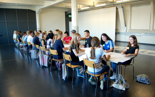 Viele junge Schüler sitzen an einem Tisch im Rahmen einer Veranstaltung der Kulturakademie.
