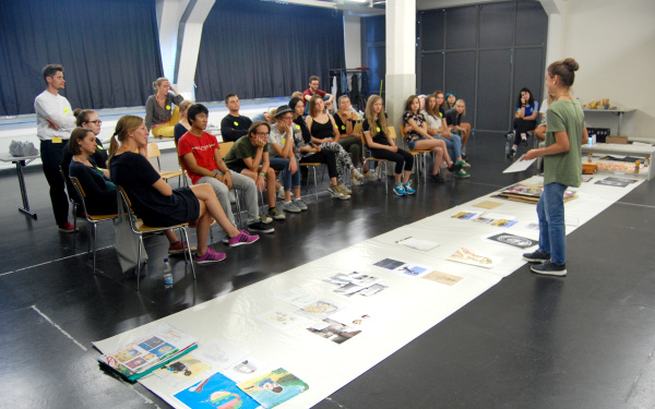 Eine Schülerin stellt einer Gruppe von Schülern verschiedene Bildwerke vor im Rahmen einer Veranstaltung der Kulturakademie.