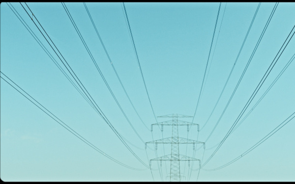 Das Bild zeigt einen Strommast vor einem türkisblauen Himmel. 