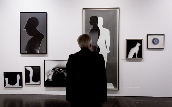 A man is standing in front of different images in black and white