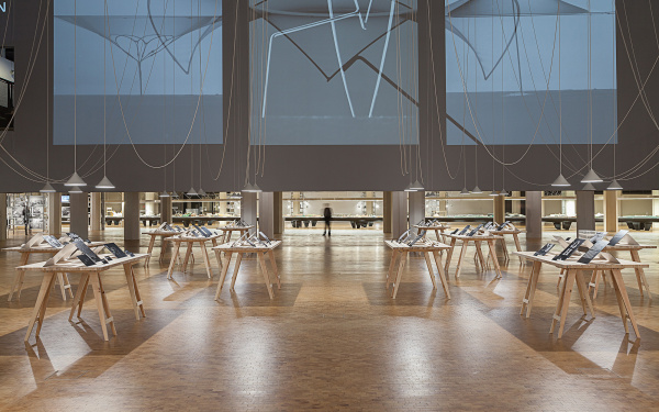 View into the Frei Otto exhibition: Tables with black-and-white-photographs, hanging ropes and a room filling screen