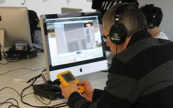 Ein Mann hält einen gelben Gameboy vor sich, mit dem er Sounds kreieren kann.
