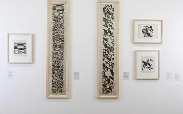 View of a white wall with six images, with abstract, black-and-white patterns.